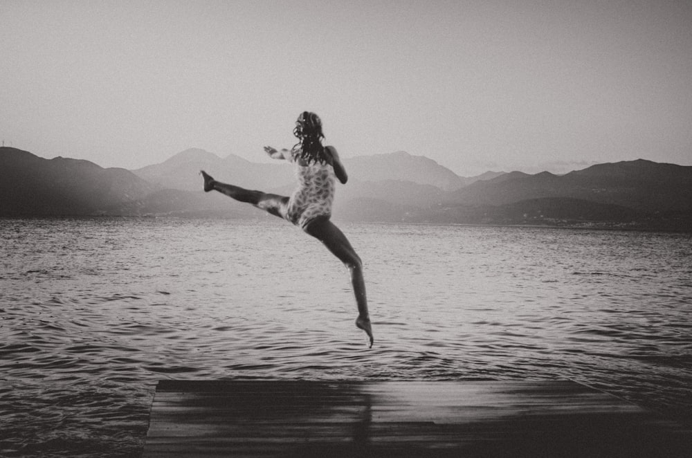 woman jumping on bridge dock