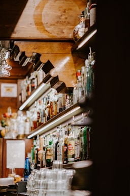 Cozy bar counter with warm lighting and bottles on shelves