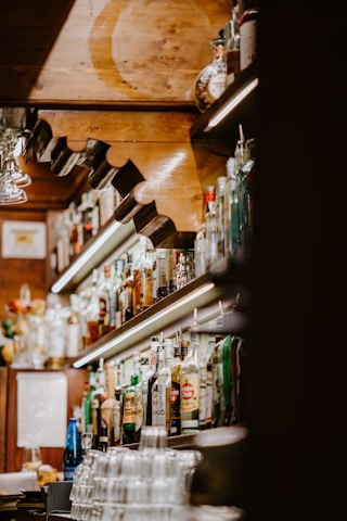 Cozy bar interior with warm lighting and bottles neatly arranged on shelves.