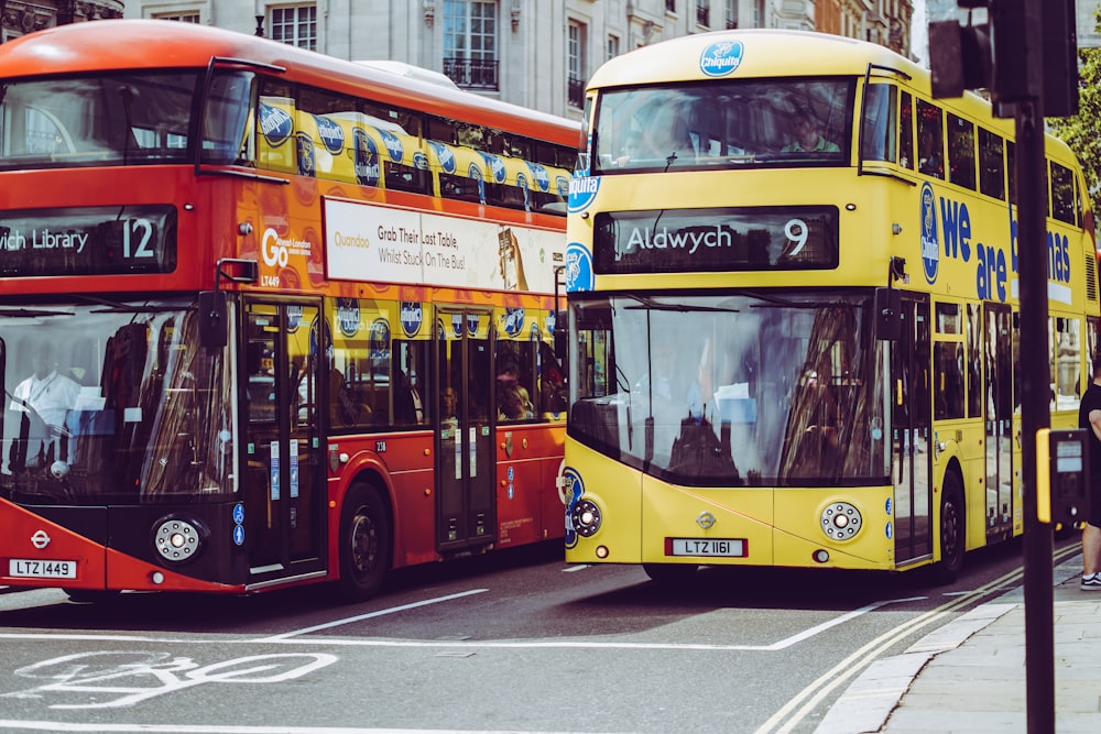 회색 콘크리트 도로에 노란색과 빨간색 2층 버스 두 대가 있습니다.