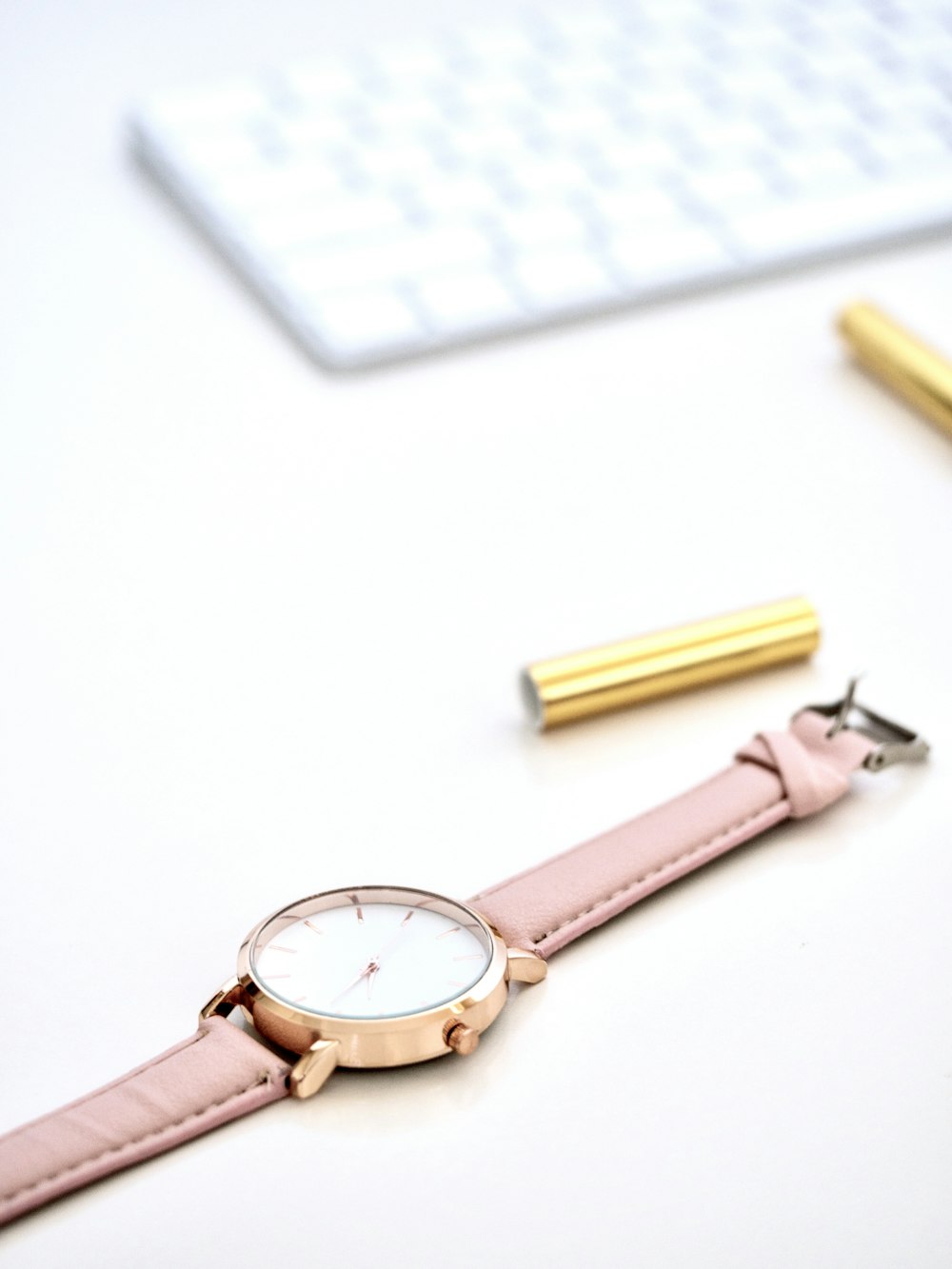 round gold-colored framed analog watch on white surface
