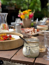 A vibrant, rustic wooden table set outdoors with colorful southern dishes and fresh sides under warm sunlight.