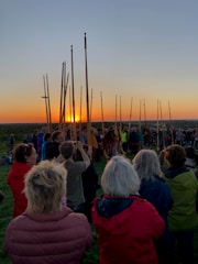 A group prayer circle gathered outdoors at sunset.