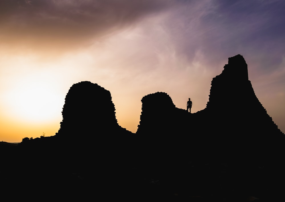 silhouette photography of person standing on cliff