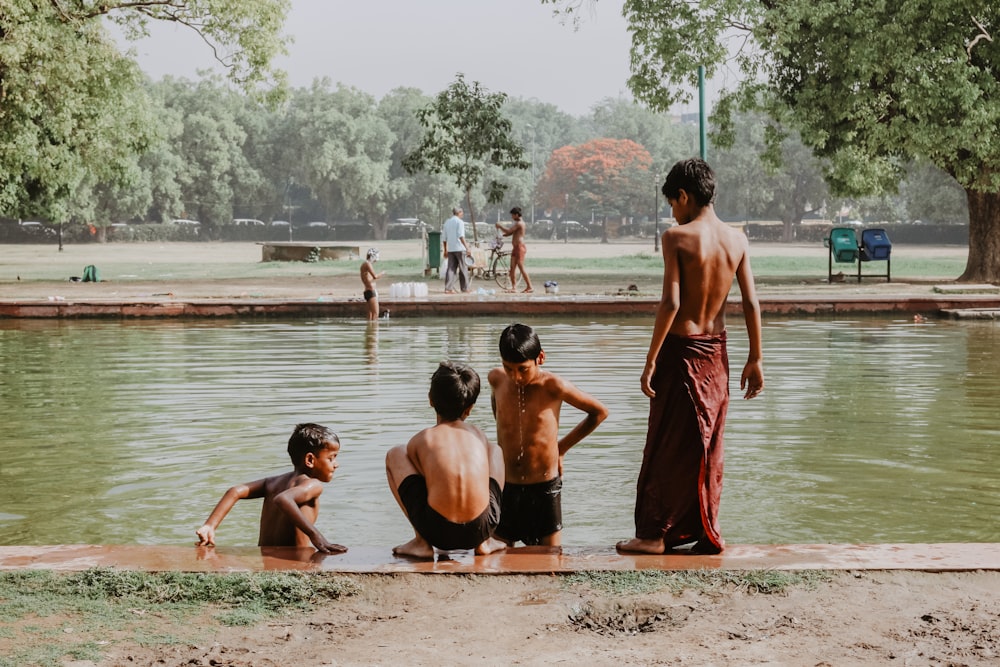 four toddlers standing near body of water