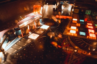 A pinball machine with vibrant, illuminated features including various colorful lights and intricate mechanical components. The board is adorned with symmetrical patterns and glowing sections, adding to the dynamic atmosphere.
