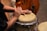 A close-up of hands skillfully playing a djembe drum in natural light.
