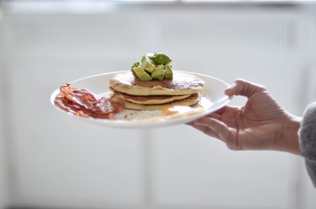 person holding pancakes on white plate