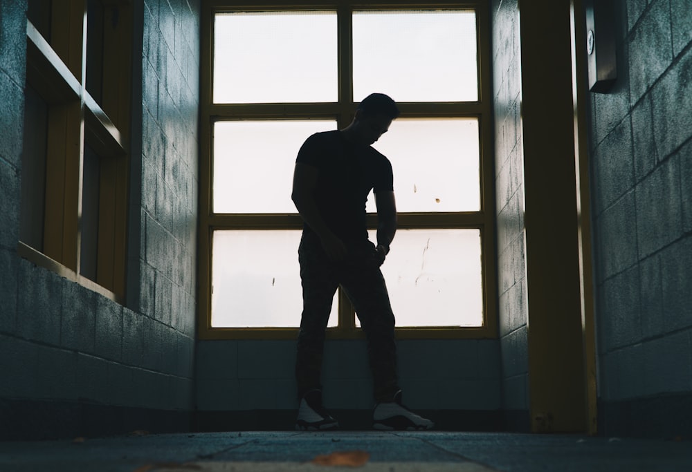 silhouette photo of a man standing near glass window