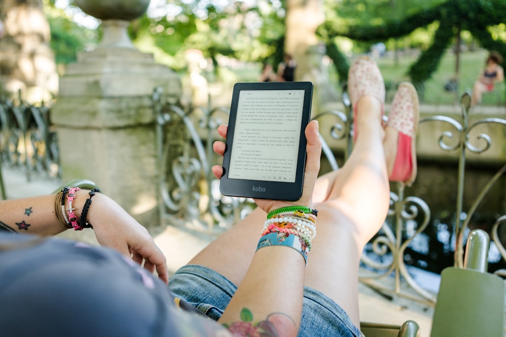 femme allongée sur une chaise tenant une tablette