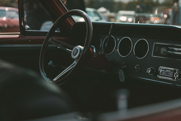 Close-up of a vintage steering wheel and dashboard with classic gauges lit softly.