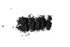 Activated charcoal powder and bentonite clay in glass bowl for DIY face mask