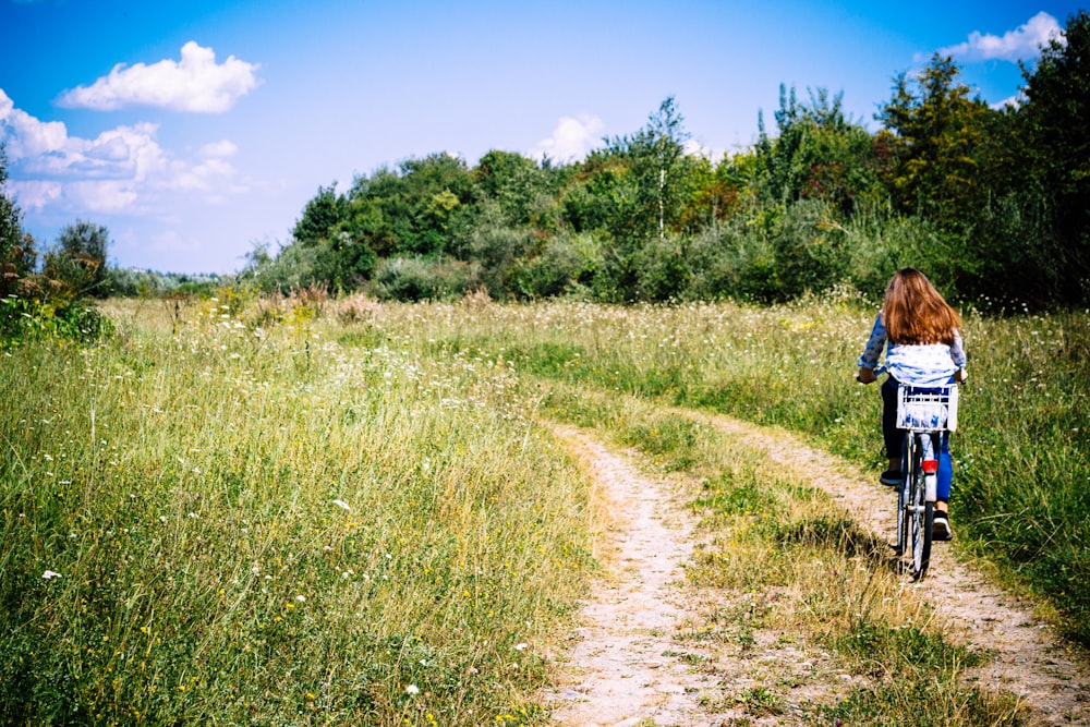 woman biking between grasses