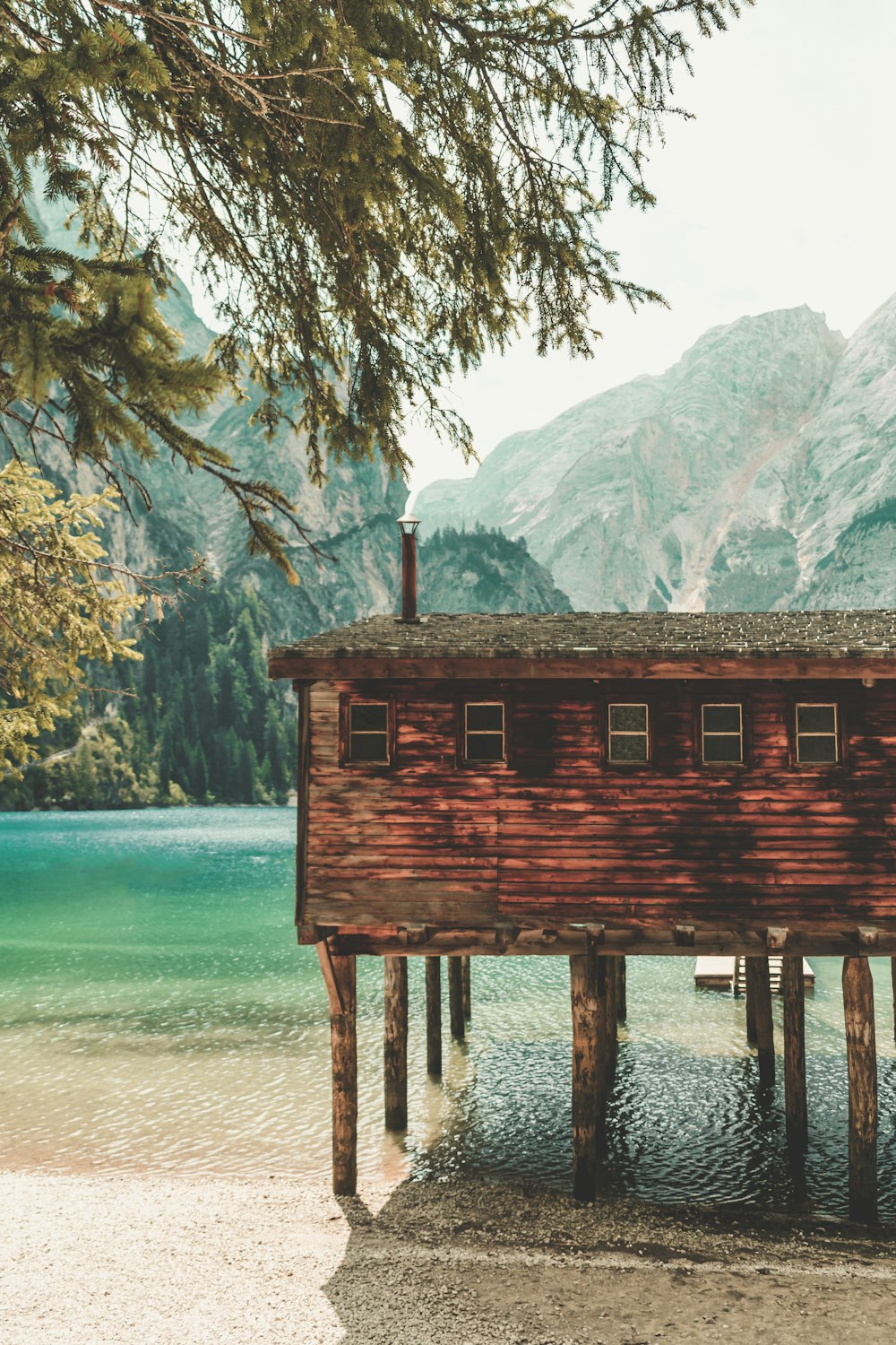 brown wooden house over sea surrounded with mountain