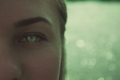 A close-up of Becky in character, eyes focused and expressive, with a subtle green backdrop.