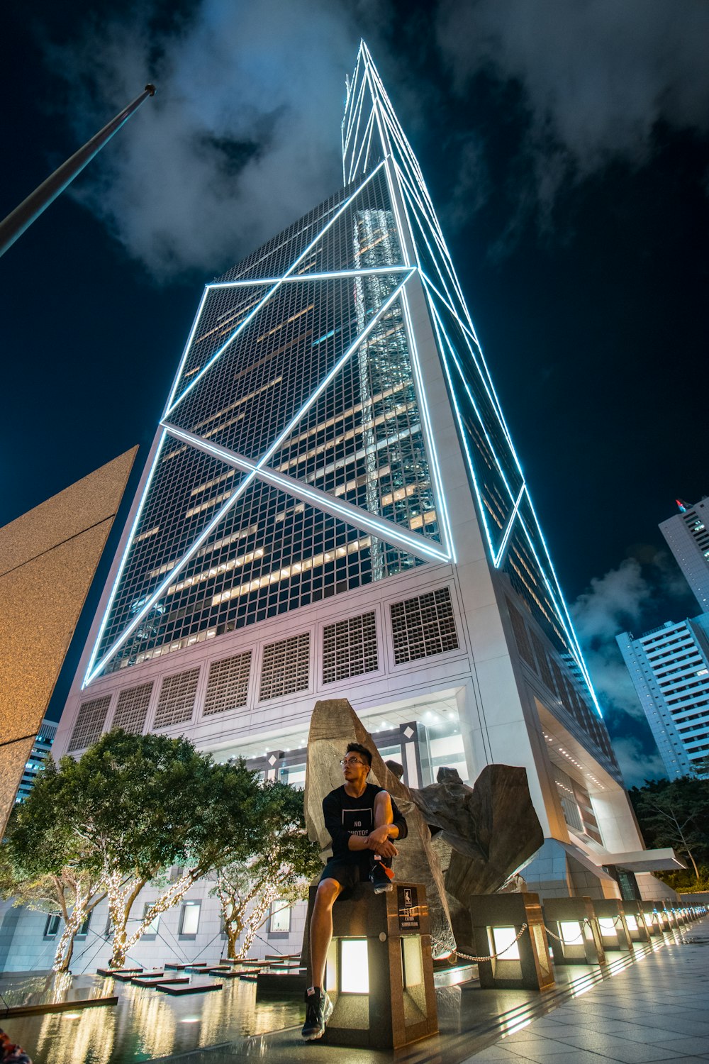 low angle photography of man seating in front of skyscraper