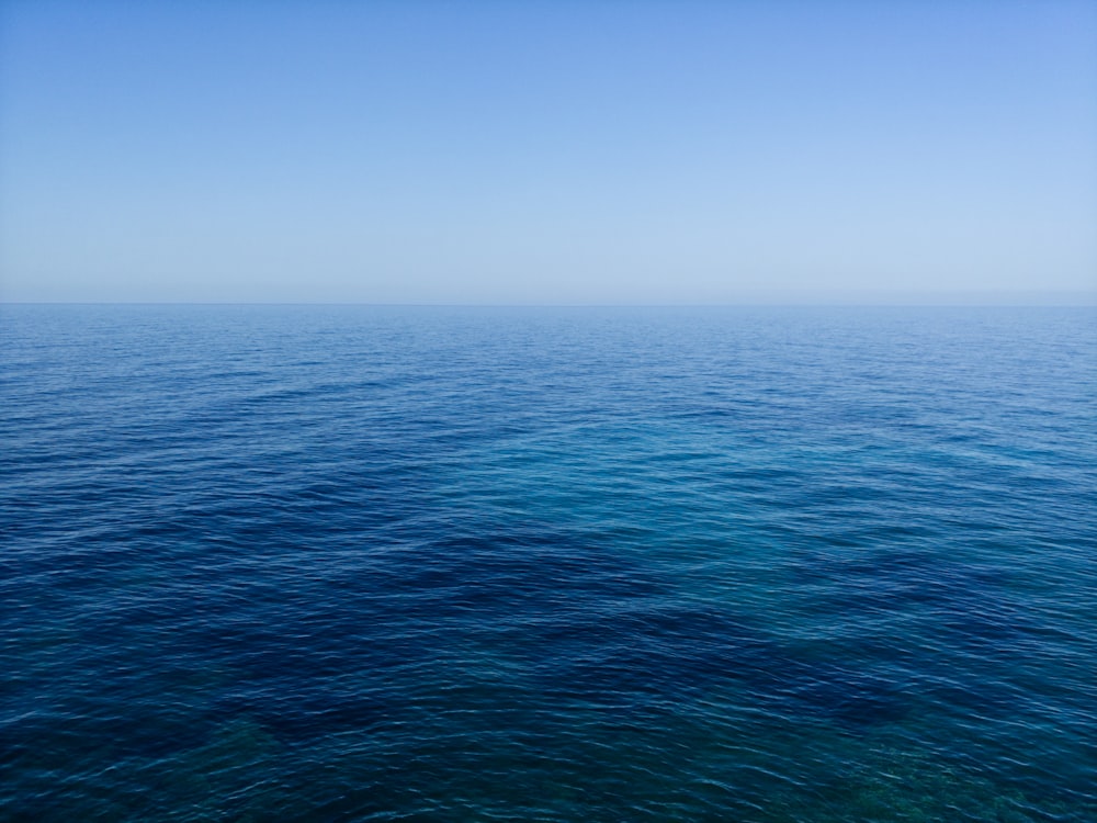 calm body of water under blue sky photography during daytime