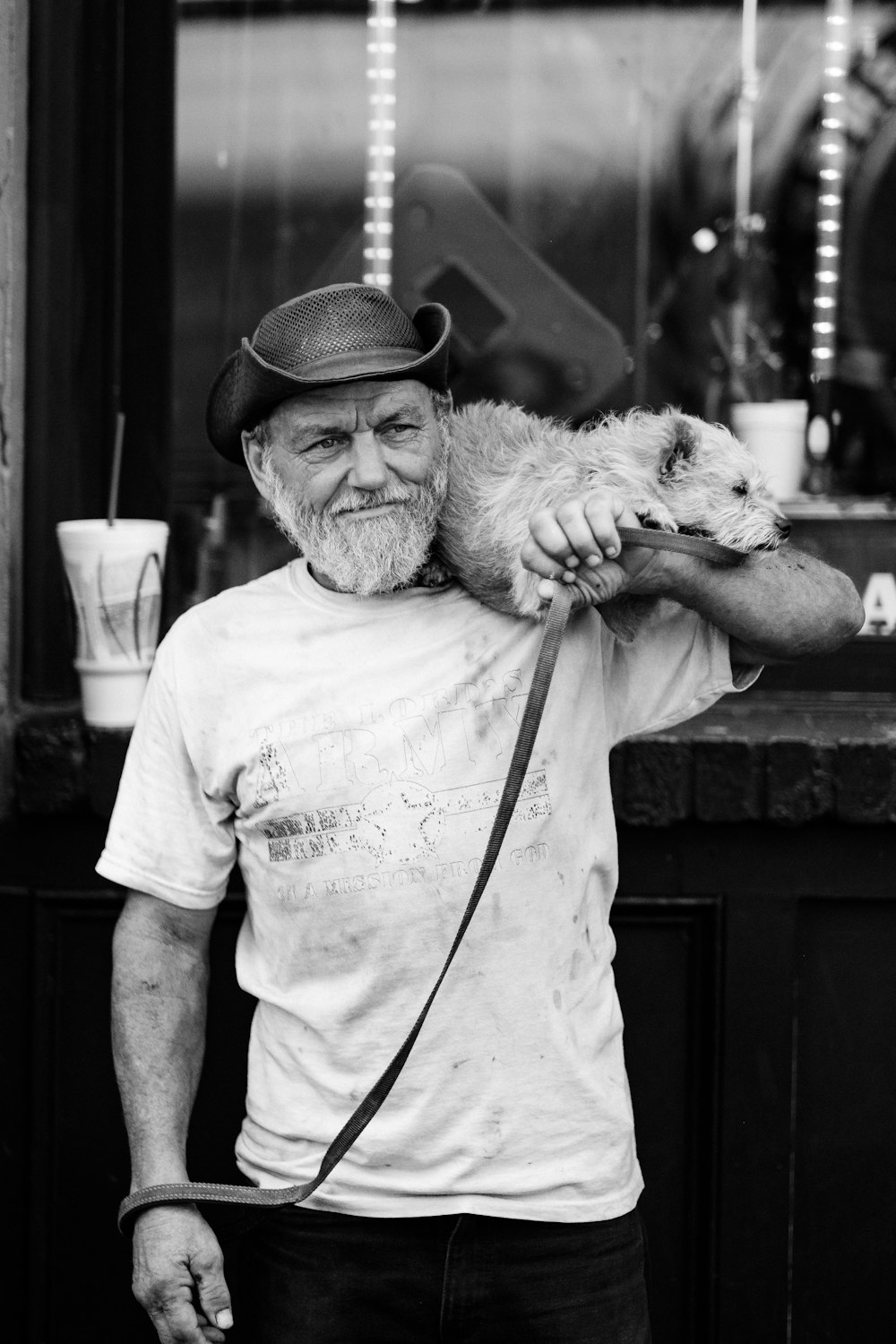 grayscale photography of a man carrying dog