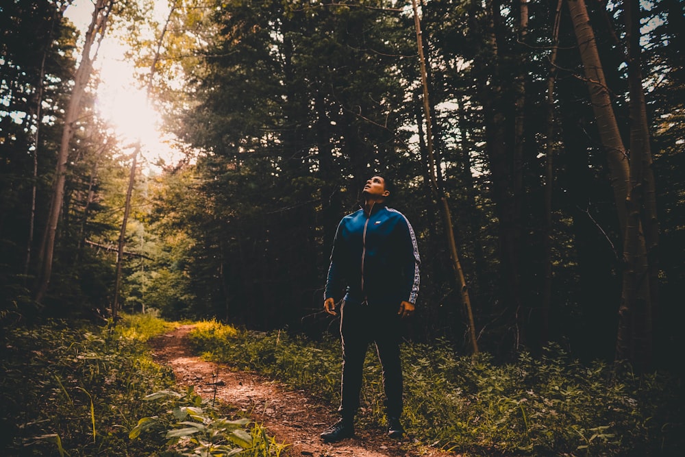 man standing near green trees during daytime