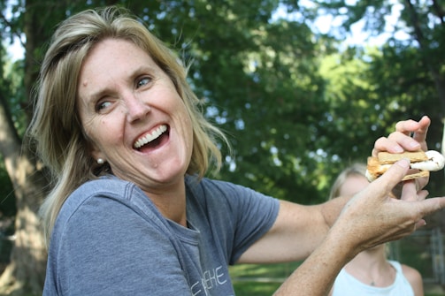 A smiling woman enjoying a healthy homemade meal outdoors, embodying sustainable weight loss.