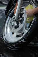 Detail shot of a technician carefully cleaning car rims with a soft brush.