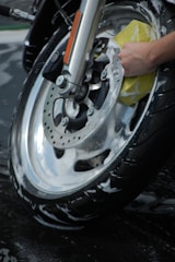A biker’s hand gently buffing a motorcycle’s scratched paint surface.