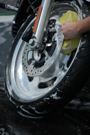 Close-up of hand applying scratch remover on a sleek motorcycle body panel.