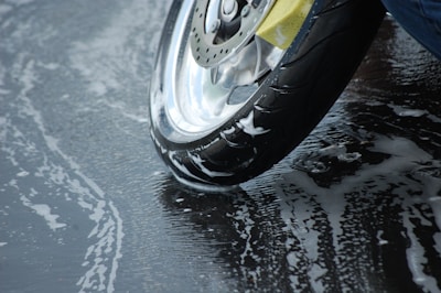 A clean motorcycle being washed with soap suds on a sunny day.