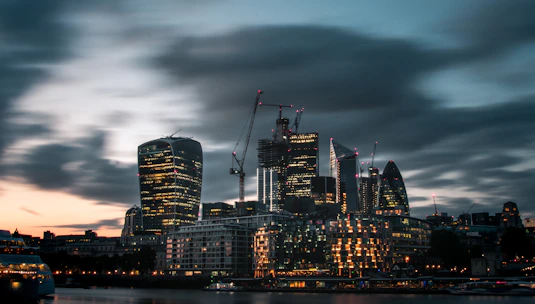 A sleek city skyline at dusk with cranes and construction sites illuminated, symbolizing ongoing large-scale projects.