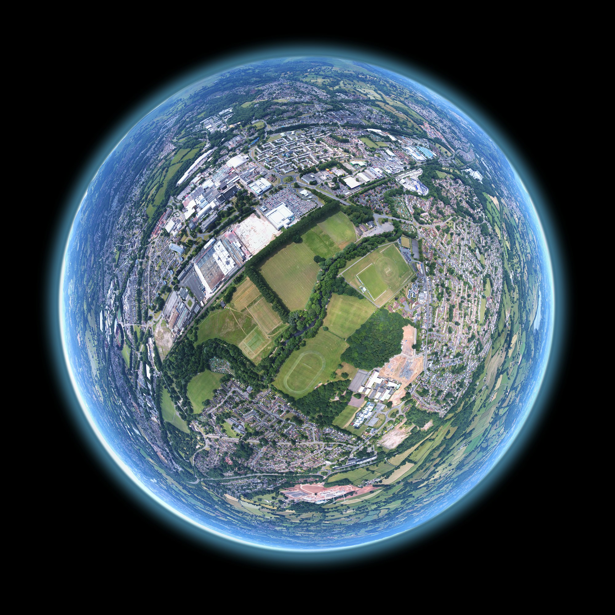 A 360 panorama stitched and warped to create the tiny planet effect. Image sequence taken by drone above a community field in Wales.