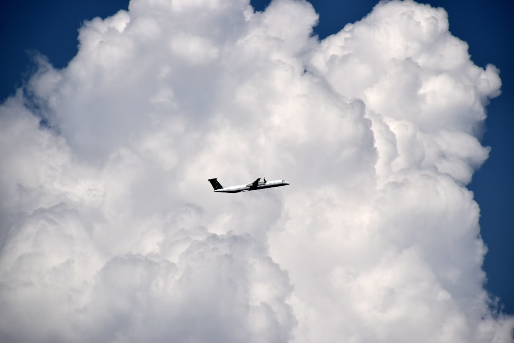 white airplane fly over clouds