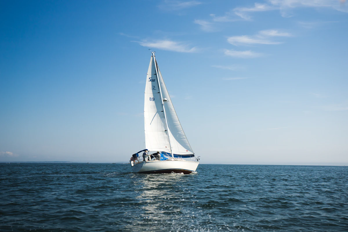 Blue and white sailboat on open ocean water
