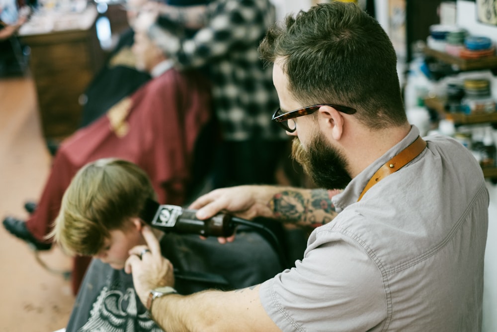 Mann rasiert dem Jungen die Haare