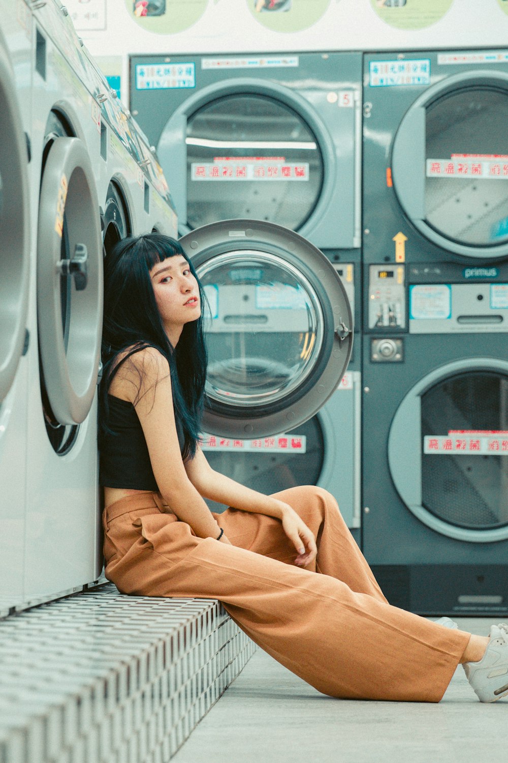 a woman sitting in front of a stack of washers