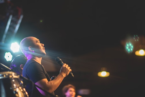 A close-up of hands holding a microphone on stage, spotlight shining softly.