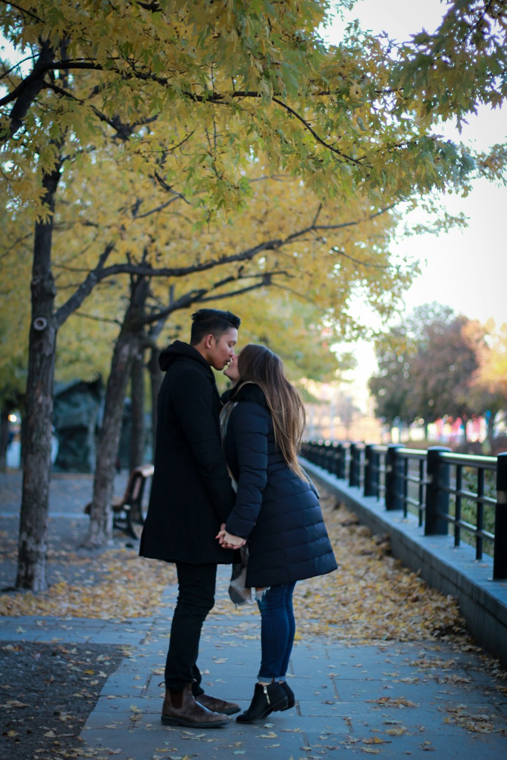 couple kissing in park under green leafed tree