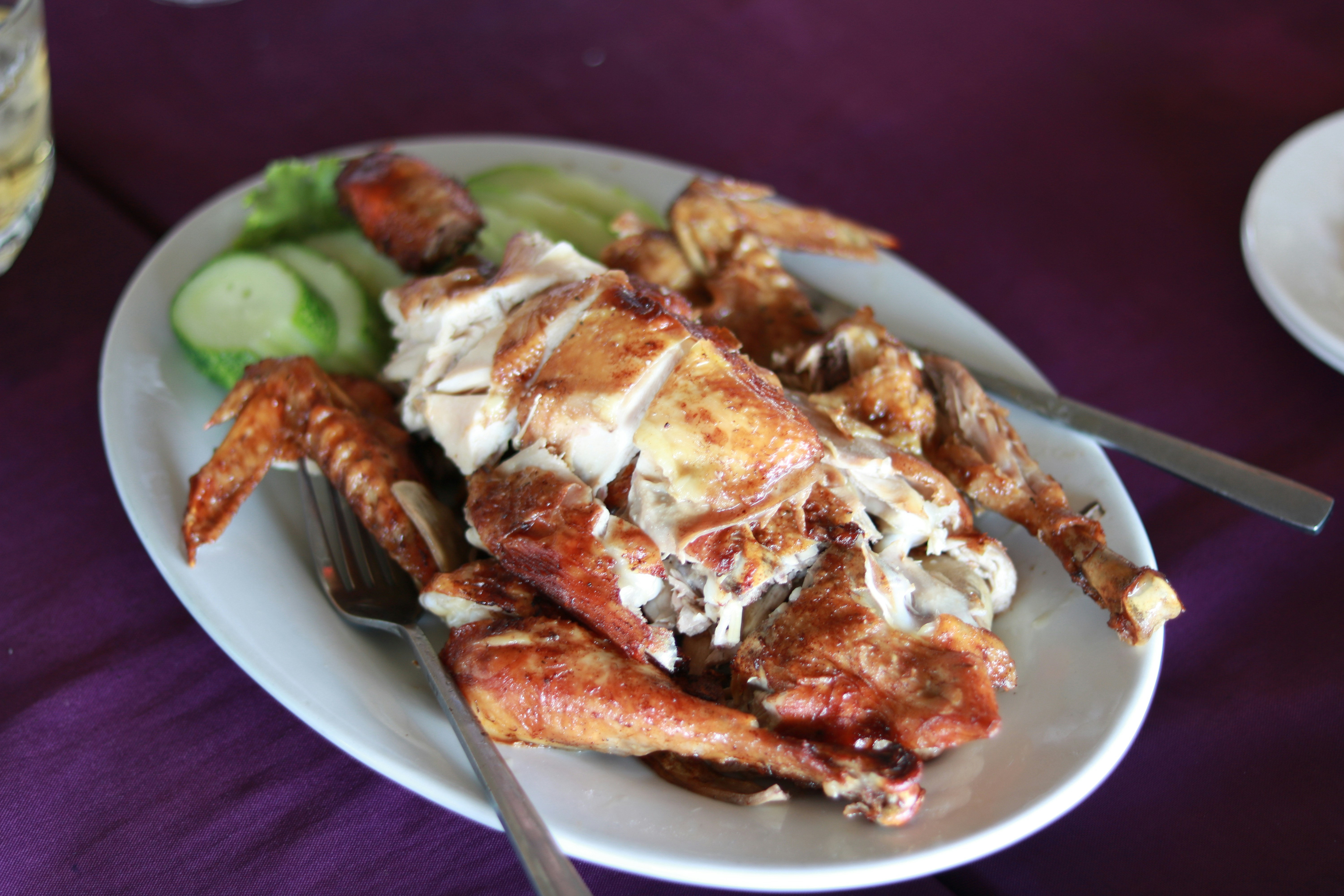 Manok rice meal with grilled chicken pieces over rice with cucumber slices and cherry tomatoes