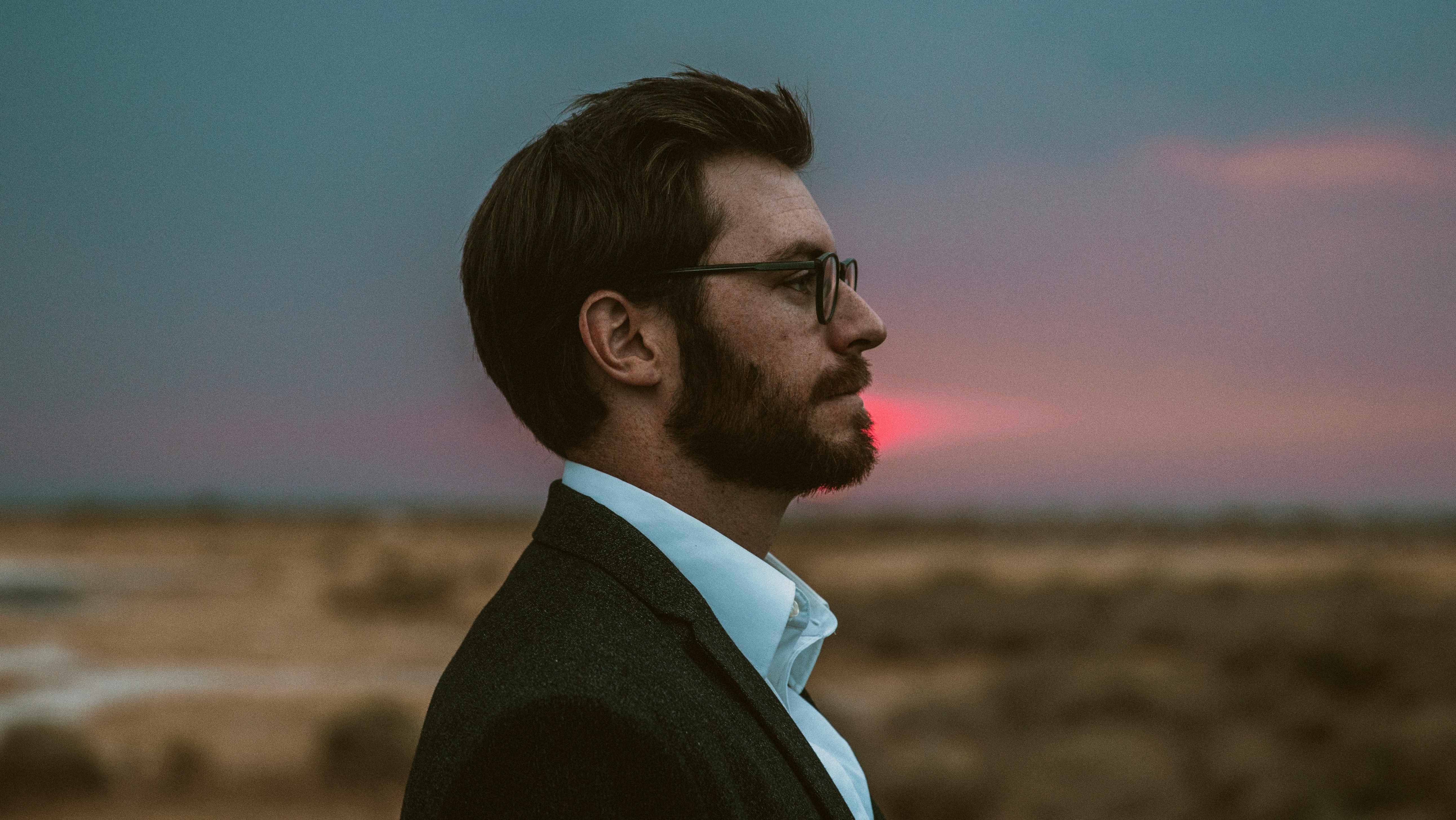 man in black formal suit wearing eyeglasses