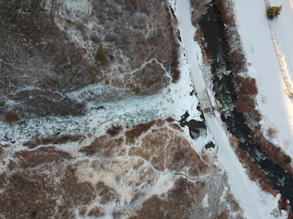Top-down aerial view of a frozen waterfall, flowing into a turbulent river.