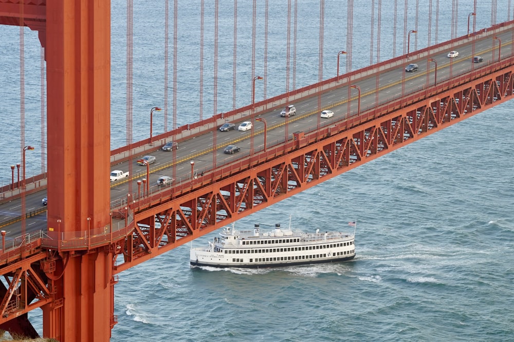 white cruise ship under concrete bridge