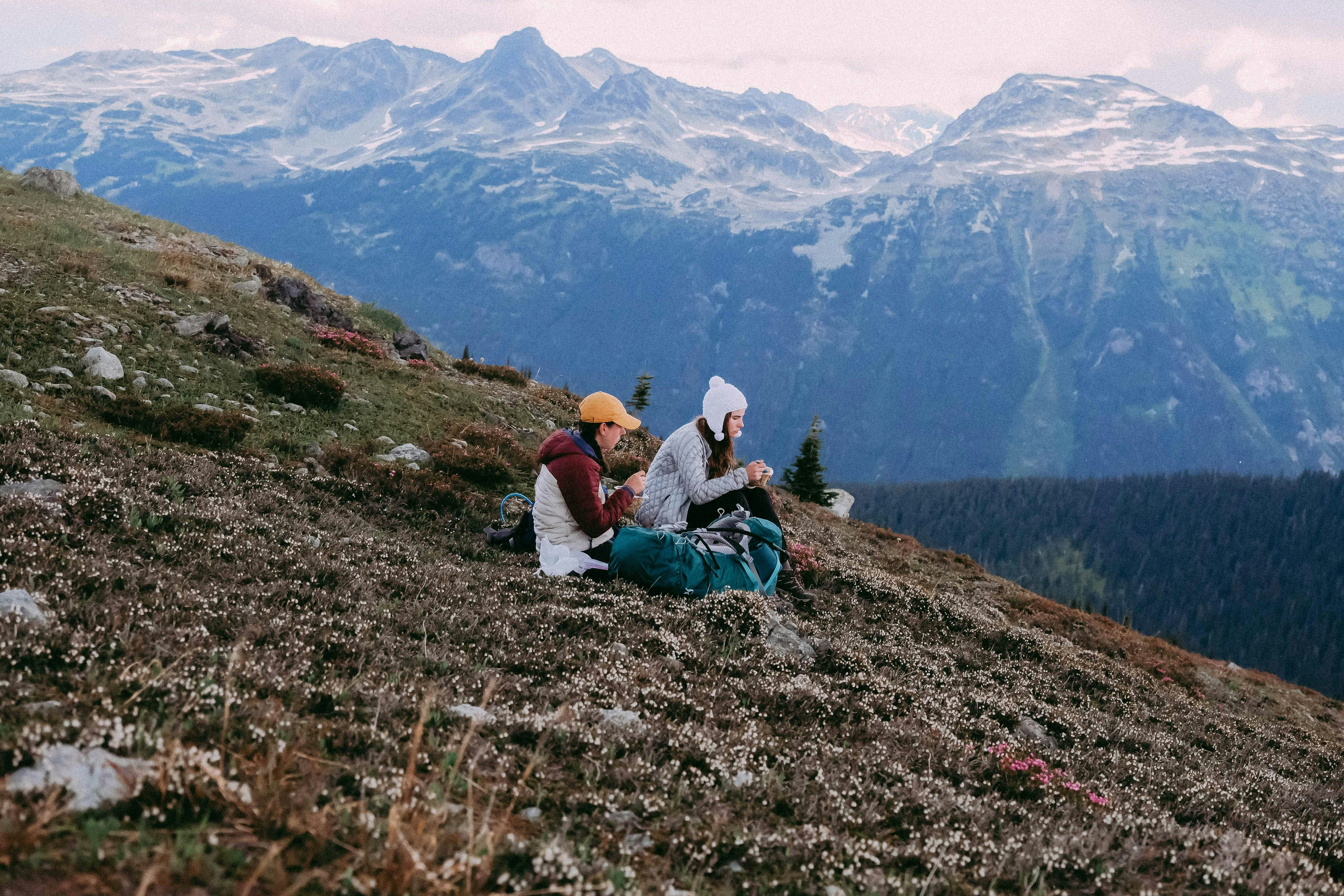 man and woman sitting on ground looking at mountain