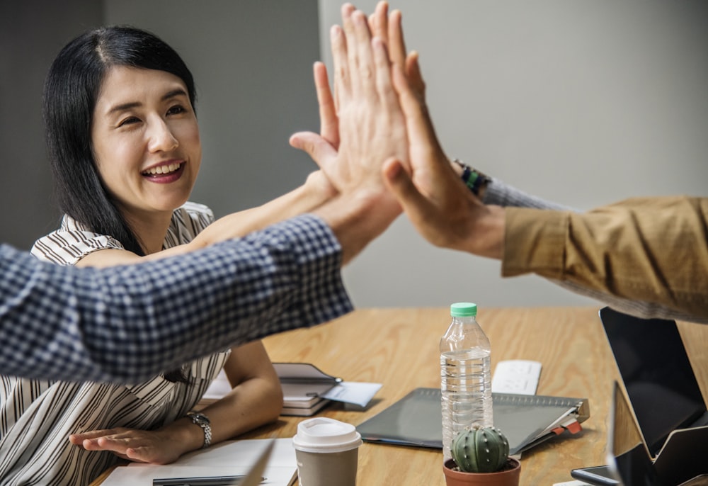 four person holding hands on brown wooden table