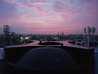 Sunset view from the radio station rooftop with antennas and city skyline in the background.