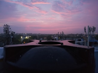 Sunset view from the radio station rooftop with antennas and city skyline in the background.