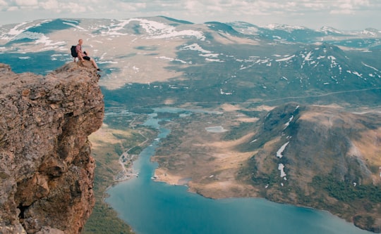person sitting on mountain cliff in Besseggen Norway