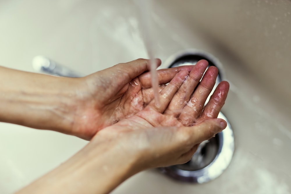 person washing hands over sink