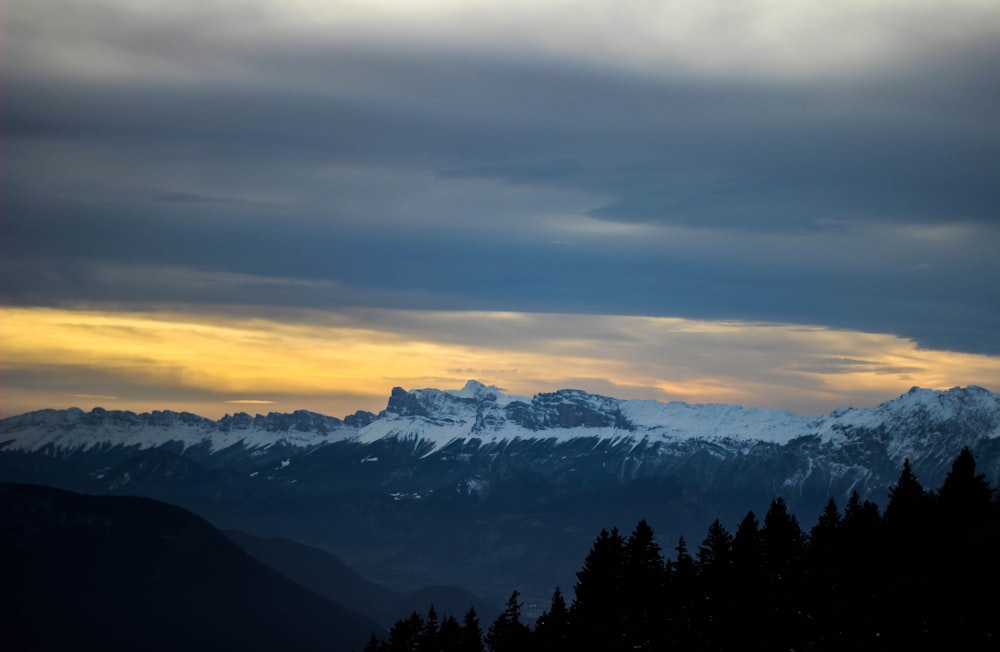 aerial photography of snow covered mountain under white cloudy skies at daytime