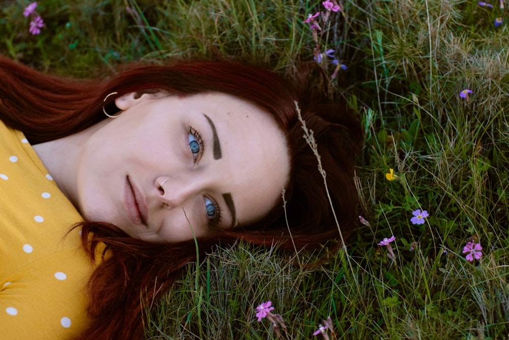 Femme en haut à pois brun et blanc couché dans l’herbe verte pendant la journée