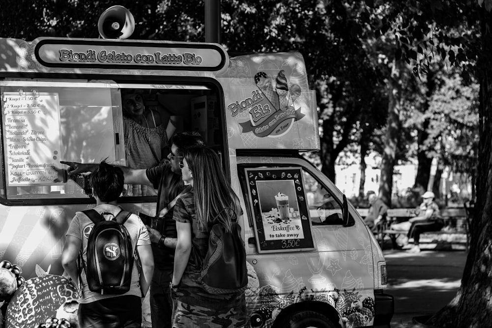 grayscale photo of people beside van store