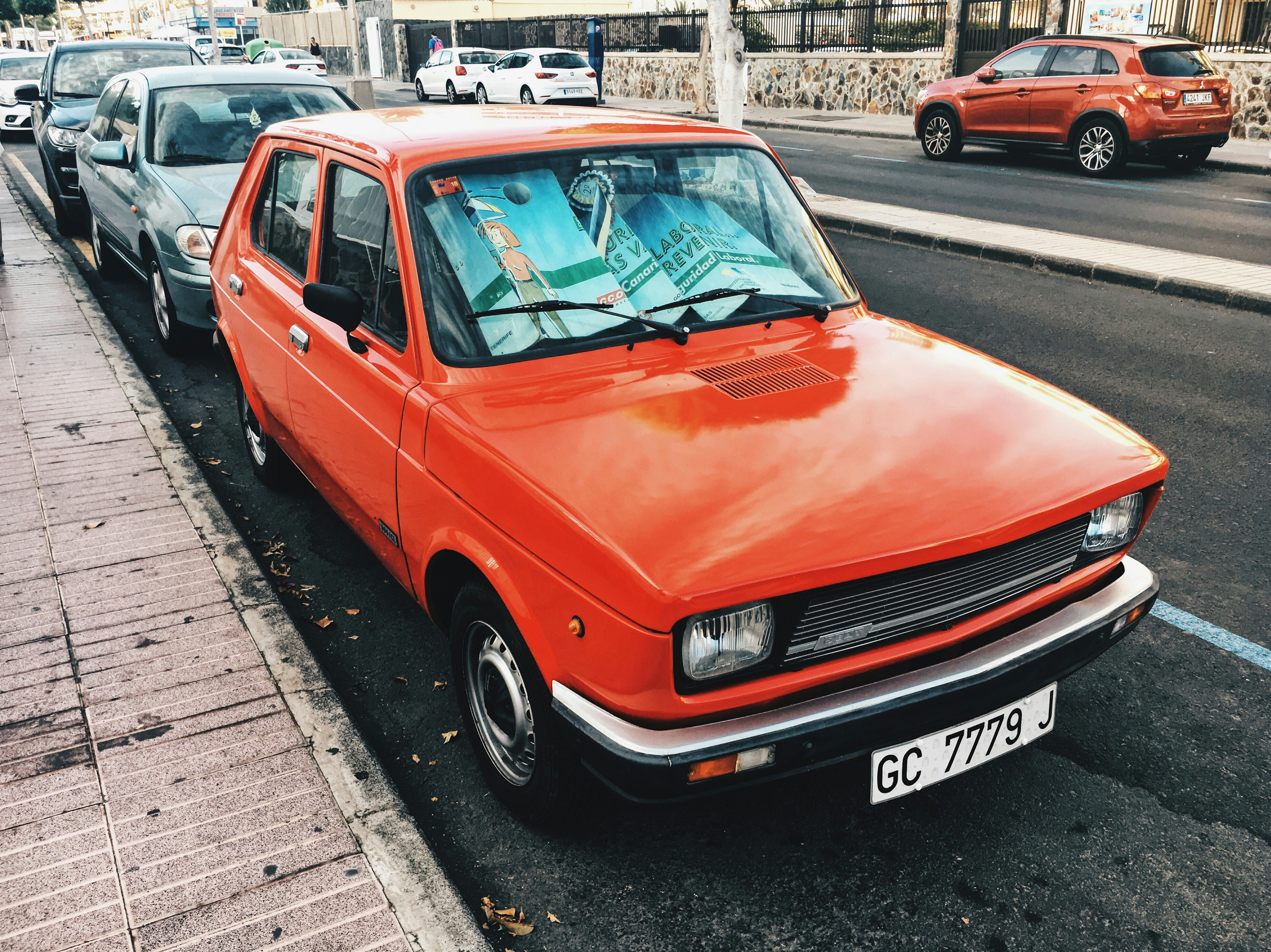 rote 5-türige Schräghecklimousine in der Nähe von Betonbordstein geparkt